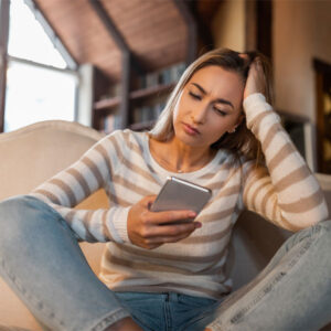 worried woman looking at her cell phone wondering, "should I confront my partners lover?"