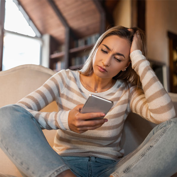 worried woman looking at her cell phone wondering, "should I confront my partners lover?"