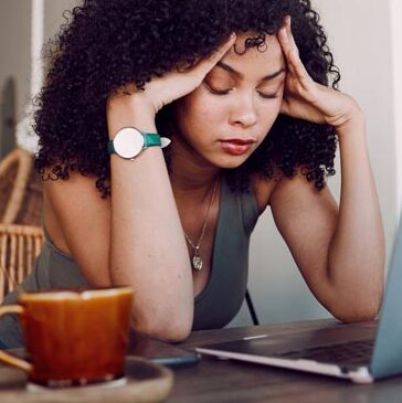 woman with her hands on her temples and her eyes closed trying to block out thoughts of her husbands infidelity