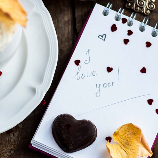 happy relationship acts of love cappuccino with a note saying i love you and heart shaped chocolate with confetti shaped hearts