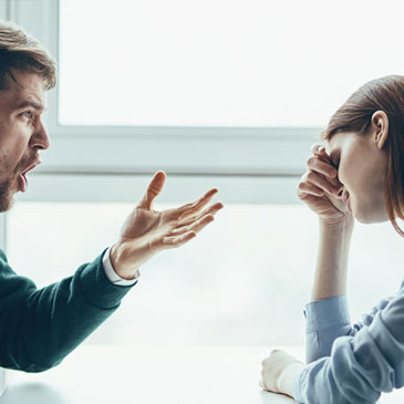 husband being verbally abusive to his wife in a cafe while wife looks overwhelmed with her emotions