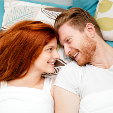 intimacy activities with ginger couple in bed staring into each others eyes smiling